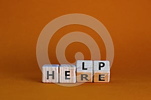 Help is here symbol. Turned wooden cubes and changed the word help to here. Beautiful orange background, copy space. Business,
