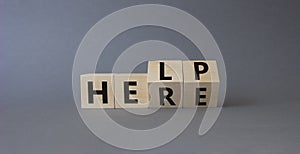 Help is here symbol. Turned wooden cubes with words Here to Help. Beautiful grey background. Business and Help is here concept.