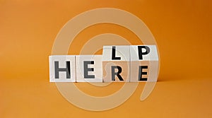 Help is here symbol. Turned wooden cubes with words Here to Help. Beautiful orange background. Business and Help is here concept.
