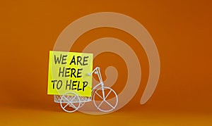 Help is here symbol. Wooden clothespin with yellow paper. Words `we are here to help`. Miniature bicycle model. Beautiful orange