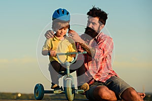 Help kid explore world. Happy loving family Father and son. Little boy wearing helmet while learning to ride cycle with