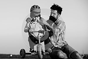 Help kid explore world. Happy loving family Father and son. Little boy wearing helmet while learning to ride cycle with