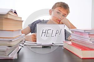 Learning difficulties, school, quarantine education concept. Tired frustrated boy sitting at table with many books. Word photo