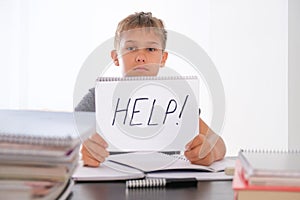 Help! Learning difficulties, school, quarantine education concept. Tired frustrated boy sitting at table with many books photo