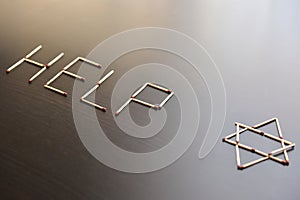 Help with magen David, Israel word from matches. Word help magen David, Israel from matches on a black wood. Concept of matches,