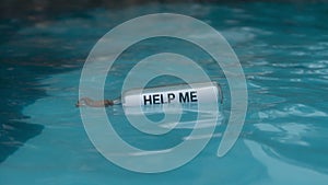 HELP ME message inside the glass bottle floating in blue water in the middle of the sea