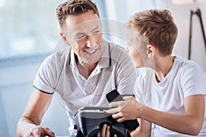 Pre-teen boy asking father how to open VR headset