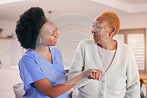 Help, nurse and holding hands of senior black woman, care and smile in house together. Caregiver, support and elderly