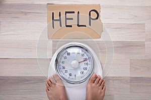 Help Sign Near The Woman`s Feet On Weighing Scale