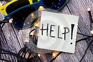 Help on Sticky note paper with sunglasses on a wooden background with lights concept for seeking help