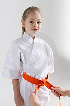 Help tie an orange belt to a child for karate lessons