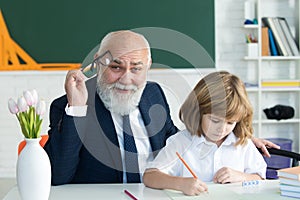 Help to learn. Old teacher with pupil. School lesson. Education concept. Old teacher with schoolboy in classroom.