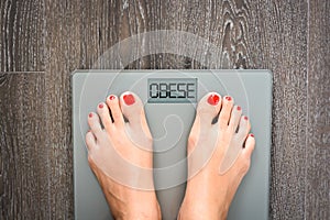 Help to lose kilograms with woman feet stepping on a weight scale photo