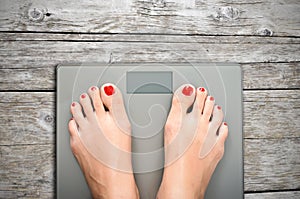 Help to lose kilograms with woman feet stepping on a weight scale photo