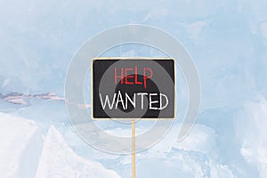 Help wanted and support symbol. Concept words Help wanted on beautiful yellow black blackboard. Beautiful blue ice background.