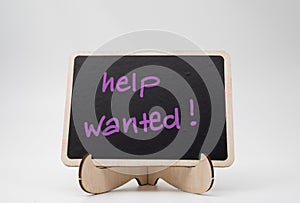 Help wanted, written on a black chalkboard with wooden frame