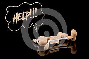 Help, Wooden Stick Figure fallen on the ground the word Help on black background