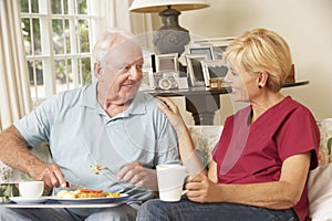 Helper Serving Senior Man With Meal In Care Home