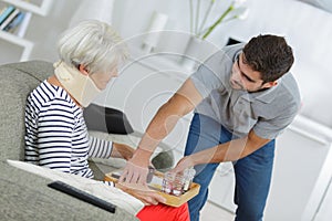 Helper serving senior woman with meal in care home