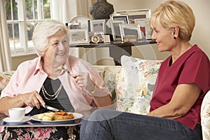 Helper Serving Senior Woman With Meal In Care Home