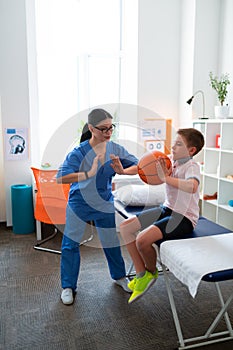 Helpful Asian physical therapist working with little boy