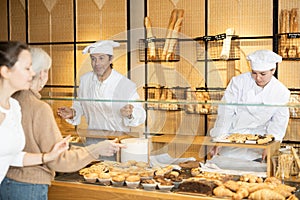 Helpful bakery salesmen selling bread and buns to customers