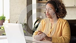 Helpful biracial woman wearing headset using laptop computer for video connection