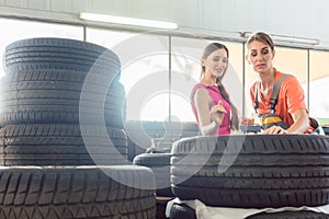 Helpful female auto mechanic checking the identification number of a tire