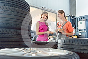 Helpful female auto mechanic checking the identification number of a tire