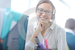 Helpful and friendly service. an attractive young customer service representative working at her desk in an office.