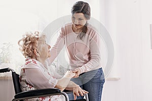 Helpful granddaughter helps her grandmother get up from her wheelchair