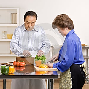 Helpful man preparing salad with wife in kitchen