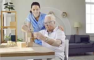 Helpful nurse in retirement home playing games with demented senior male patient photo
