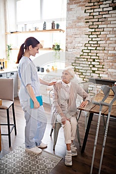 Helpful nurse wearing uniform talking to patient