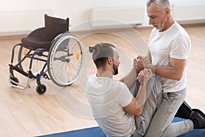 Helpful orthopedist assisting the handicapped in the gym