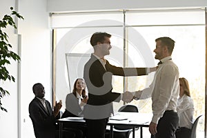 Helpful proud boss handshaking praising male worker express appreciation photo