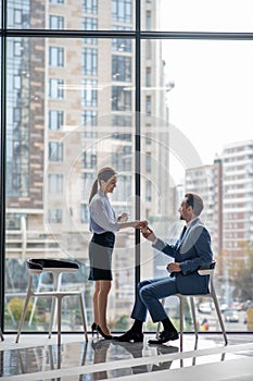 Helpful secretary bringing morning coffee to her boss in the morning