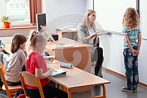 Helpful teacher talks to a student standing at the blackboard