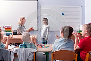 Helpful teacher talks to a student standing at the blackboard