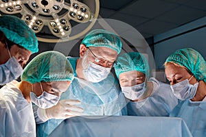 Helpful team of caucasian surgeons in operating room with surgery equipment