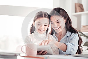 Helpful understanding mother teaching her funny energetic daughter reading