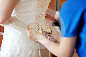 Helping the bride to put her wedding dress