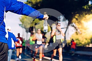 A helping hand delivers a bottle of water to a runner in a running race for him to drink