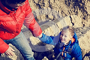 Helping hand- little boy helped by father in mountains