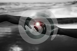 Helping hands abstract art in black and white background. Hands of two people reaching out each other to touch the light.