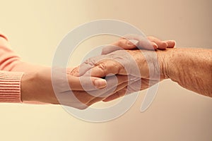 Helping hands on light background, closeup. Elderly care concept