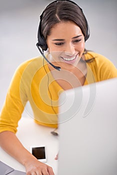 Helping her clients with finesse. Shot of a young customer service representative wearing a headset while sitting by her