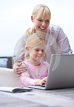 Helping her master the digital world. A young mother teaching her daughter how to use a laptop.