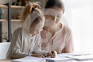 Helping young mom engaged in learning activity with preteen daughter