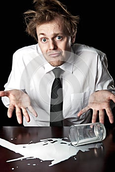 Helpless businessman with spilled milk on table